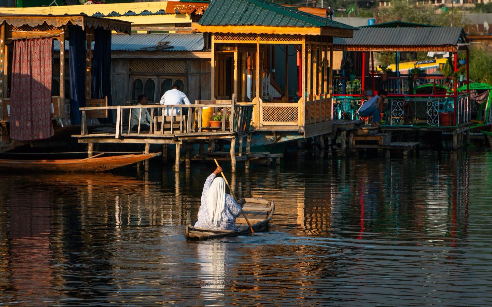 A carved houseboat on Dal Lake with a shikara alongside